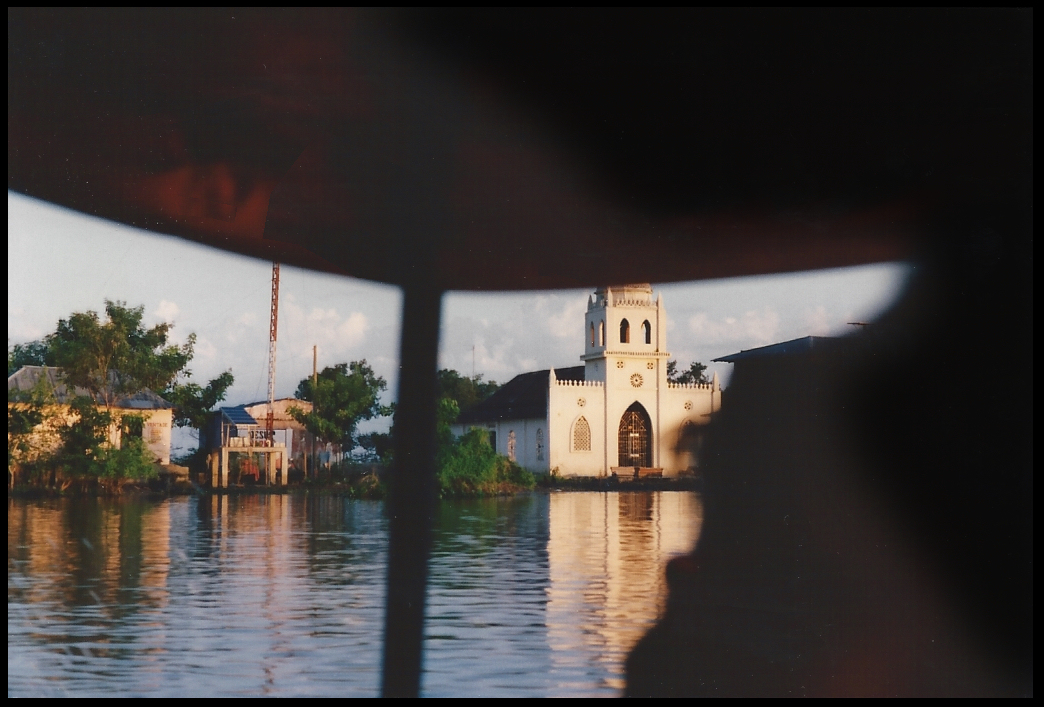 small town on river warrants cute
            church, caught from fast-moving river launch with roof
            blocking