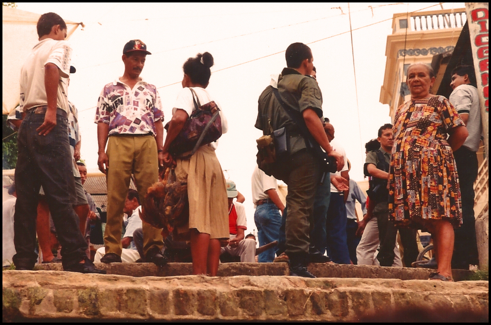 2 soldiers in sporty explorer
              uniform holding AK47s in 2 hands kibbutz with locals at
              top of Santisima Cruz' main dock (seen from below in a
              launch)