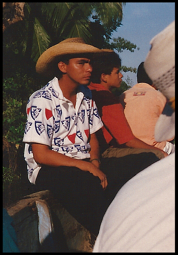 dark-skinned young man in bright shirt and Colombian
              straw hat looking off into distance thoughtfully