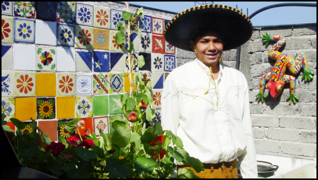 16-year-old Mexican boy in charro (Mexican rodeo) shirt
            and sombrero with Mexican talavera frog and tile hodgepodge
            plus nasturtium and geranium