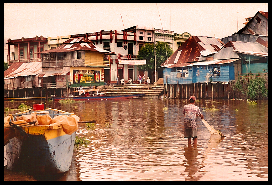 Rio Mojana opposite-bank view
              of main-dock waterfront Santisima Cruz with Pedro pulling
              in a net in foreground