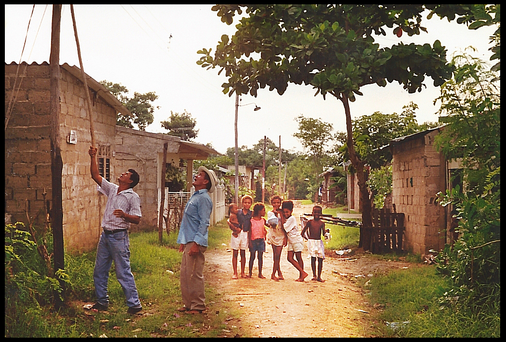 family men fix electric line
              with long pole while neighborhood kids pose