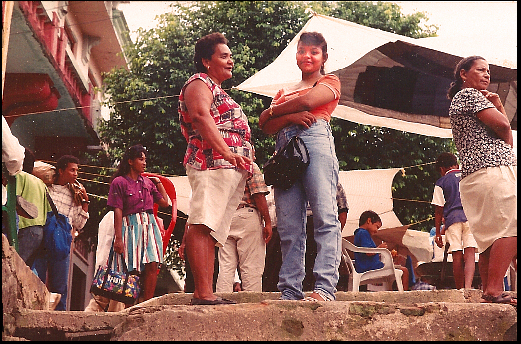 warm and glowing Sandi with
              her mother Victoria at the top of the main step-dock, busy
              market-day plaza behind them