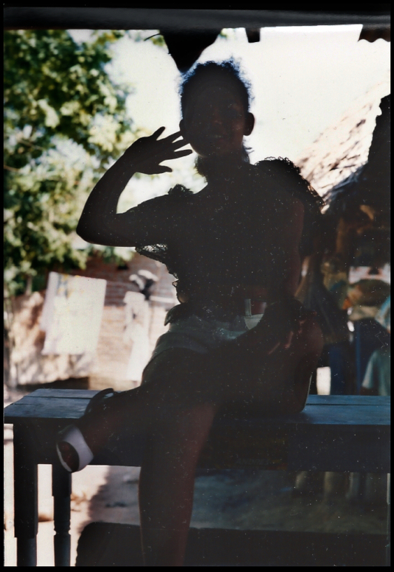 Sandi seated with hand to
              cheek, in silhouette