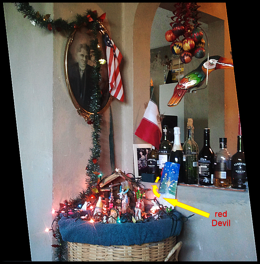 Christmas-lit creche scene atop wicker
              basket surrounded by family photos, wine bottles and
              glazed toucan