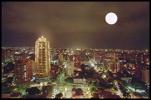 sprawling, mostly 2-story 3rd-world
              city at night with some 10- and 20-story apartments,
              headlights on boulevards, and moon