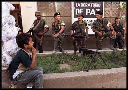 little boy sits looking into distance
              as 5 FARC rebels guard building housing peace talks