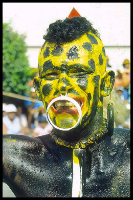 painted black body, yellow face with
              black spots, rings in nose and ears, grimacing, like
              African witch doctor