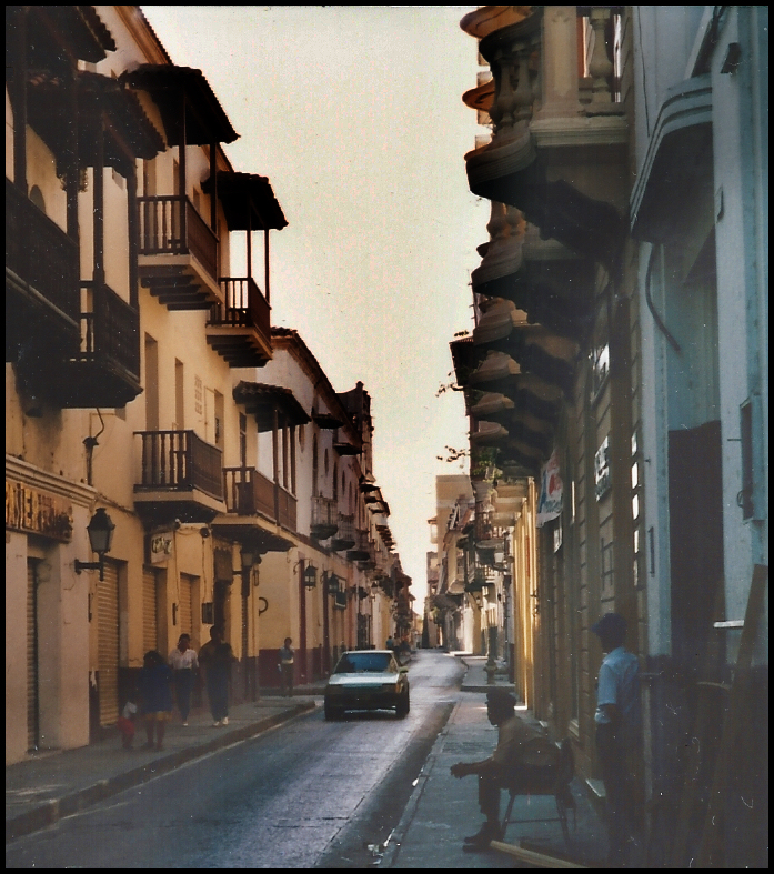 narrow street darkened by
              overhanging carved wooden balconies in 'Old Town'
              Cartagena