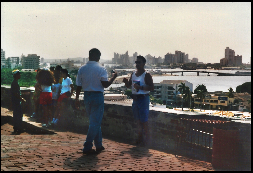 tourists on the ramparts of
              old fort, city of Cartagena in the distance