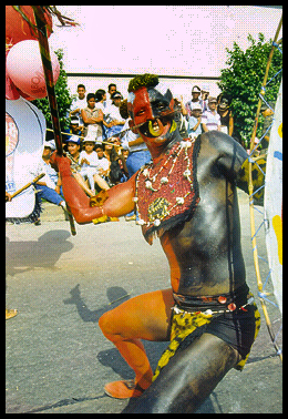 half mottled jester, half
              devil, perhaps the intent is Colombian jungle warrior,
              since carrying primitive spear and shield