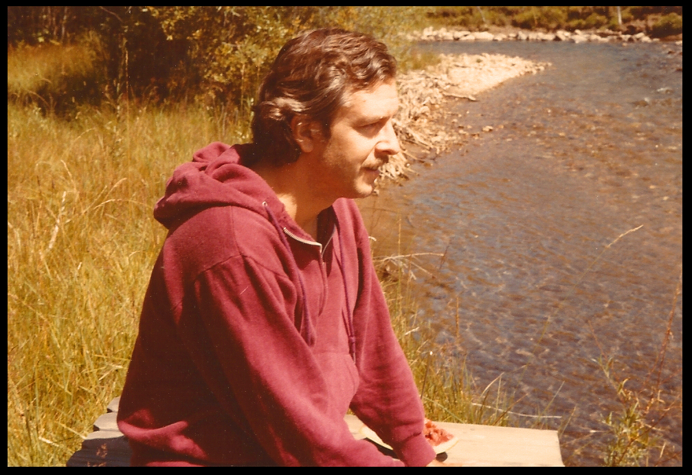 mj sits looking across creek,
            which runs from top to bottom with grassy banks