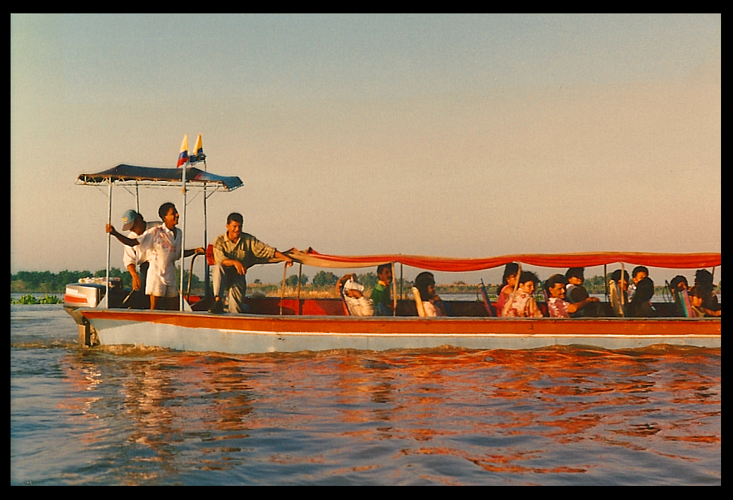 red and blue river launch with
            two Colombian flags, 20 or so passengers and 3 crew plies
            the Mojana or Cauca