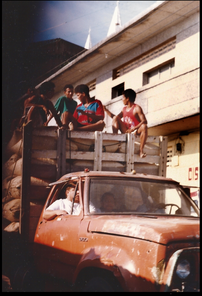 beaten up truck hauls tons of loaded
              gunny sacks, barefoot boys atop