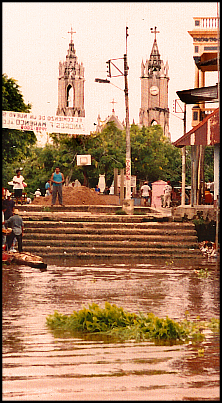 santisima cruz church seen from river
              past dock steps, people and plaza