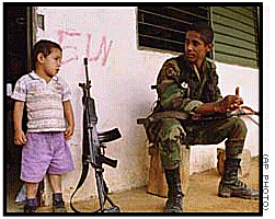 little boy in doorway of
              ELN-graffiti-ed house guarded by soldier