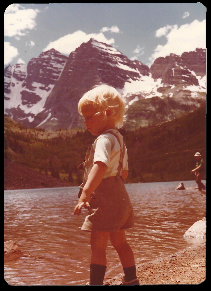 blond 3-year-old boy in
              foreground, Maroon Lake with fisherman, and Colorado's
              famous 'Maroon Bells', 2 similarly shaped mountains
              huddled like 2 bells