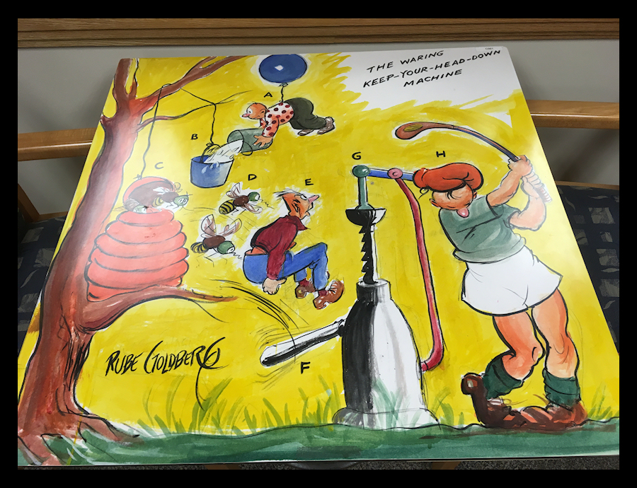 color tabletop cartoon by Rube
              Goldberg of a fantasy contraption for keeping your head
              down while golfing, named jokingly for Fred Waring