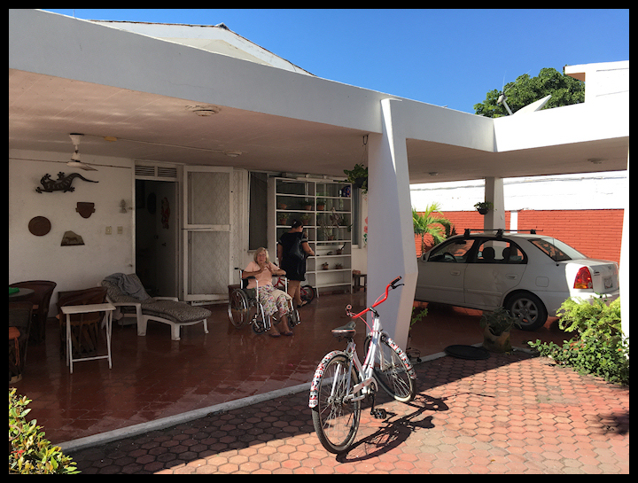 color photo of back patio at Pacific beach
                house, elderly woman in wheel chair