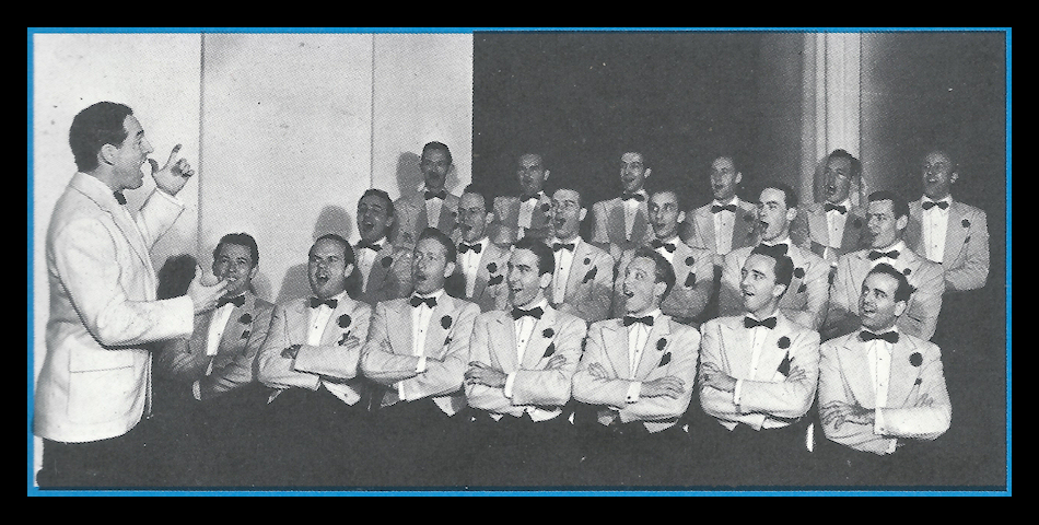 19 men seated with arms folded
          identically, all formally dressed identically with dark
          bowtie, boutonniere and pocket hanky, singing to Fred Waring's
          direction