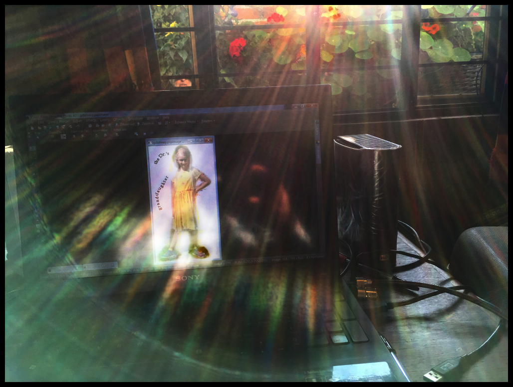 light
                  from the Dr.'s Mexican patio garden is filtered into
                  rainbow rays around a photo of his granddaughter he is
                  doctoring on his laptop, while he, with camera, is
                  reflected in the laptop screen